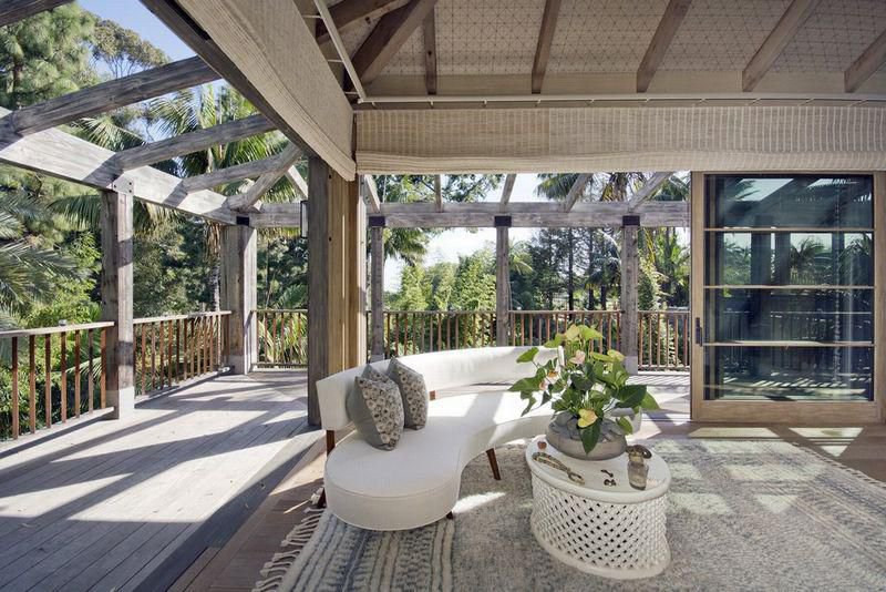 Covered terrace with natural wood beams, tropical garden views, and seamless indoor-outdoor living at a private Malibu estate.