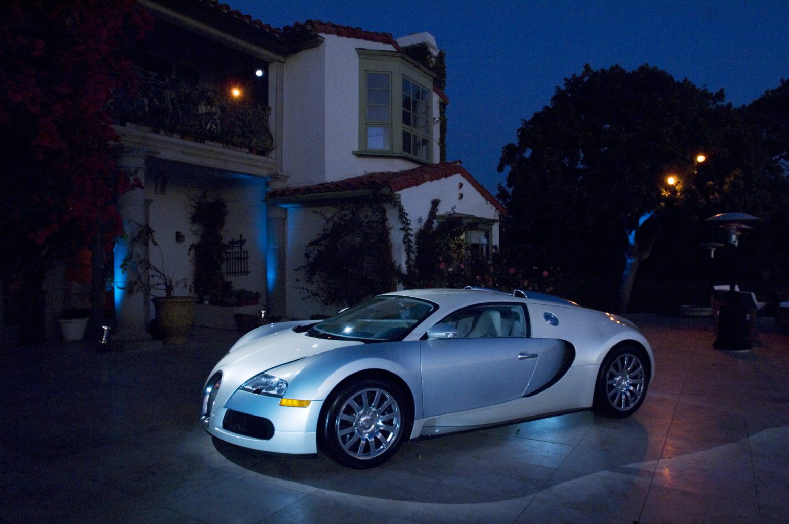 Bugatti Veyron arriving at an elegant private estate for an exclusive evening event featuring Mediterranean architecture and sophisticated event production.