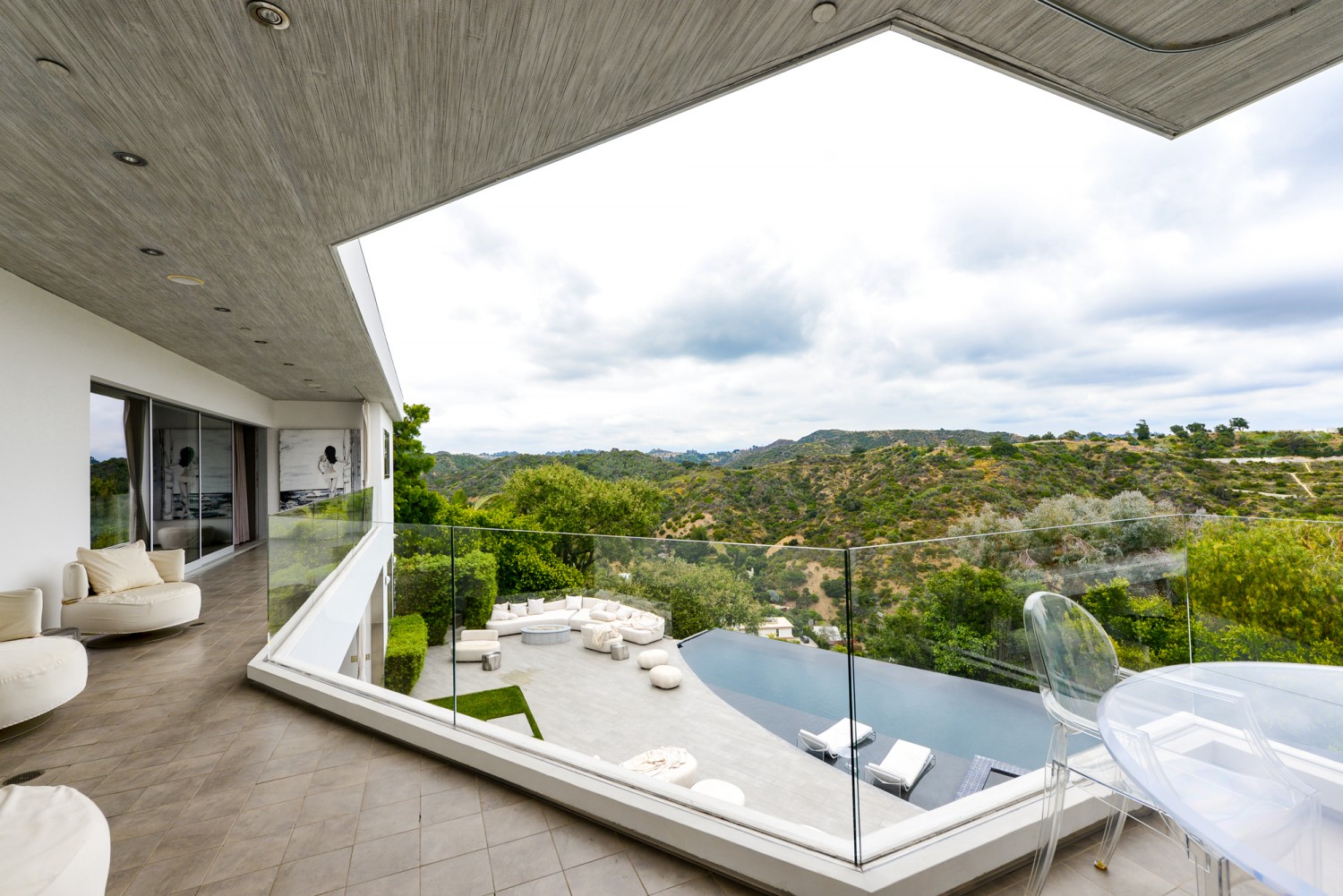 Covered balcony overlooking the infinity-edge pool and panoramic canyon views at a modern Bel Air estate rental.