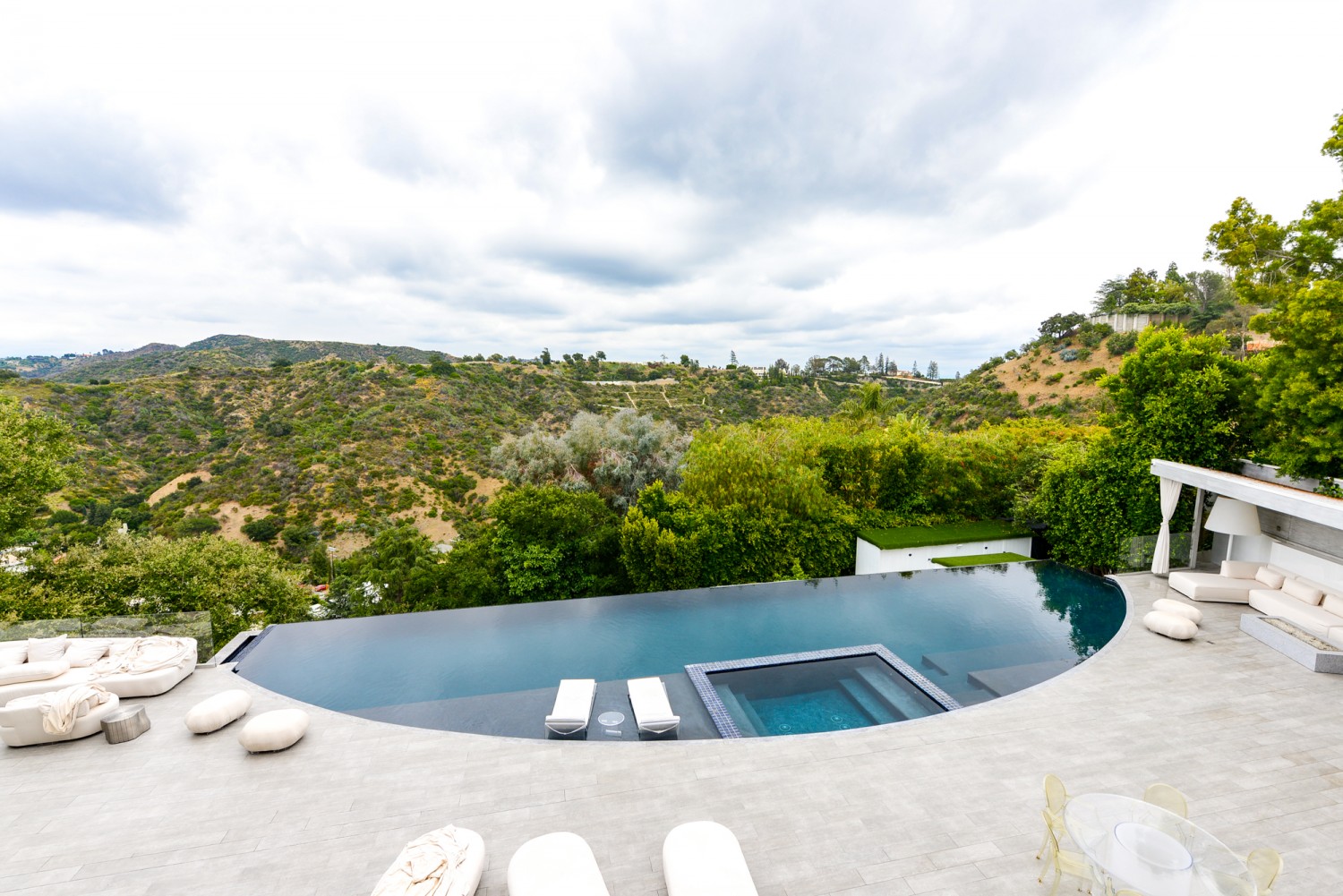 Infinity-edge pool overlooking panoramic canyon views with resort-style outdoor entertaining spaces at a modern Bel Air estate.