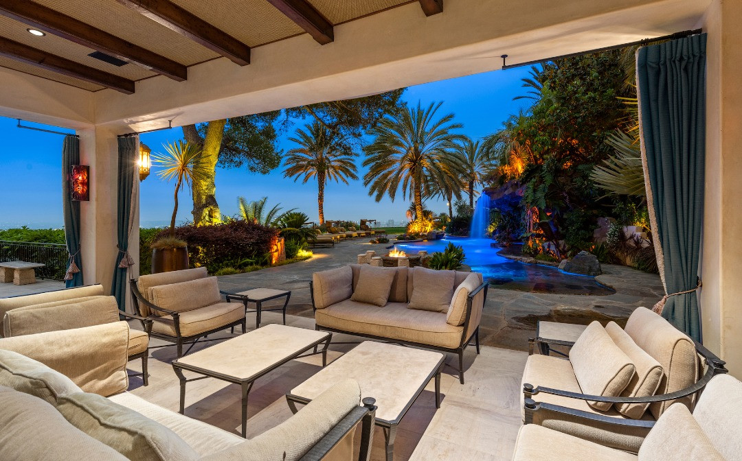 Resort-style swimming pool with dramatic waterfall, tropical landscaping, and panoramic city views.