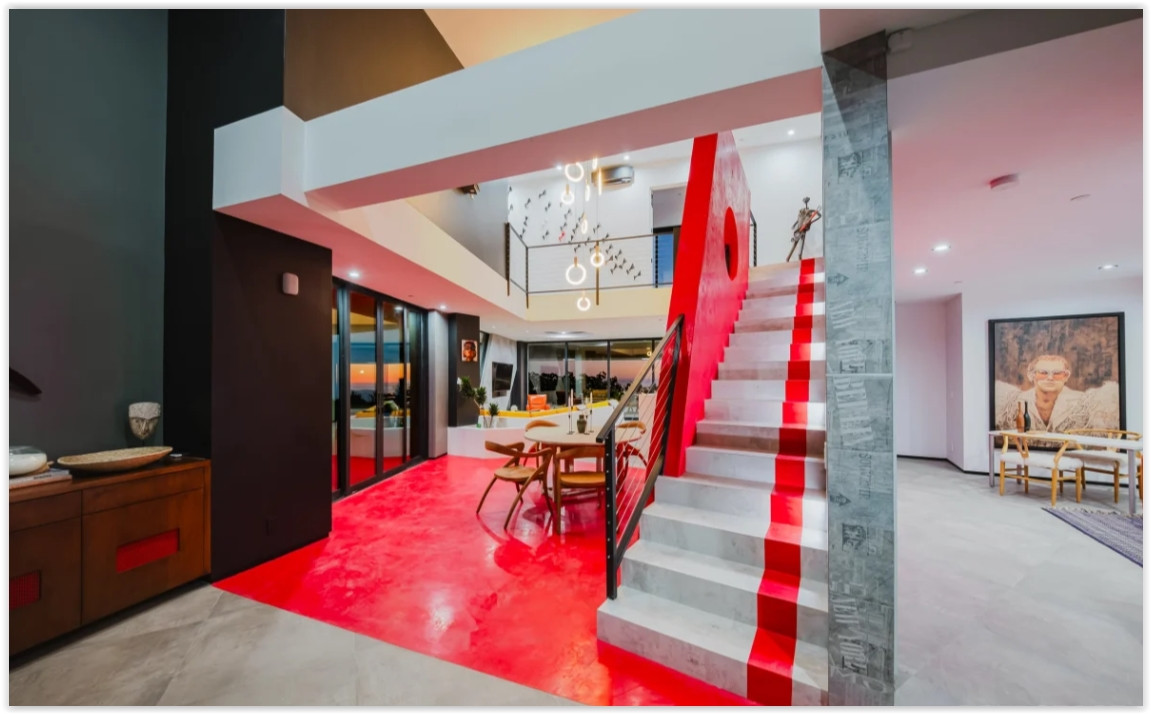 Upper-level gallery featuring dramatic contemporary architecture, skylights, statement artwork, and open views throughout a modern Malibu retreat.