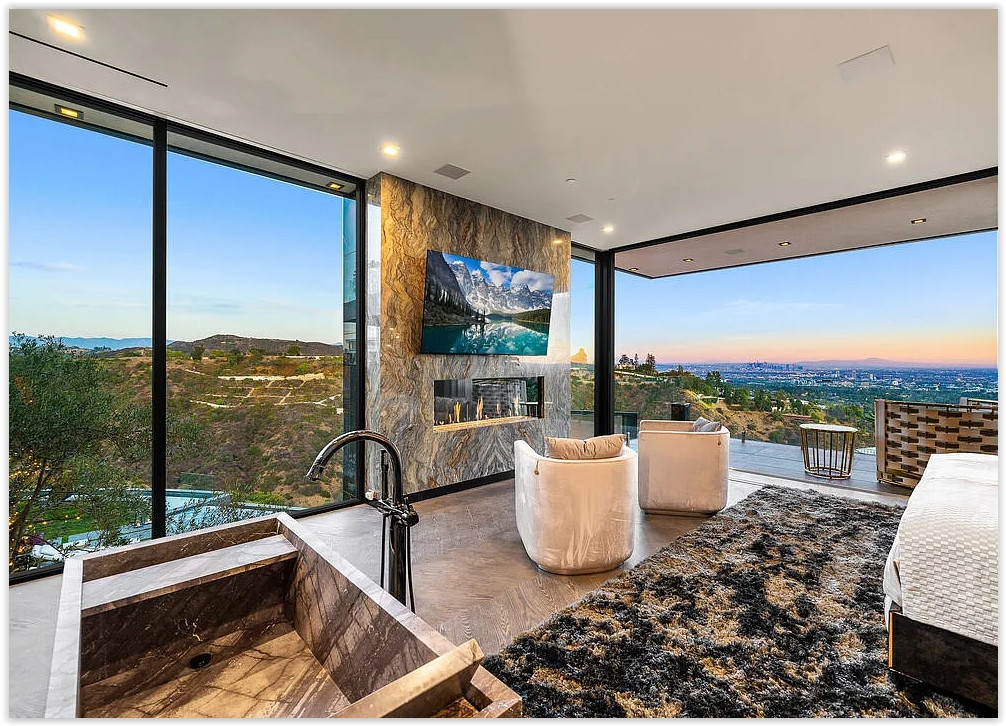 Luxury primary suite with soaking tub, fireplace, floor-to-ceiling windows, and panoramic Los Angeles skyline views
