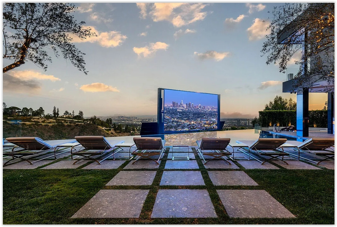 Infinity pool overlooking Los Angeles with a large outdoor movie screen, luxury lounge chairs, and panoramic city views.