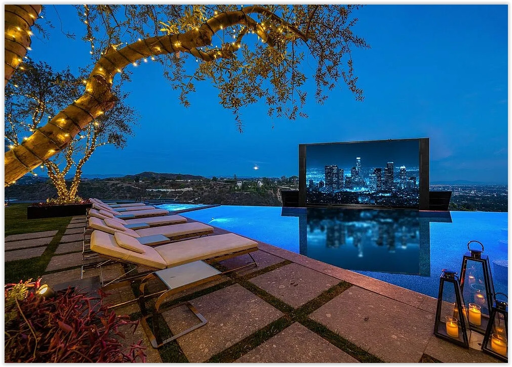 Infinity-edge pool overlooking panoramic Los Angeles city views with outdoor cinema screen and luxury lounge seating at a Bel Air estate rental.