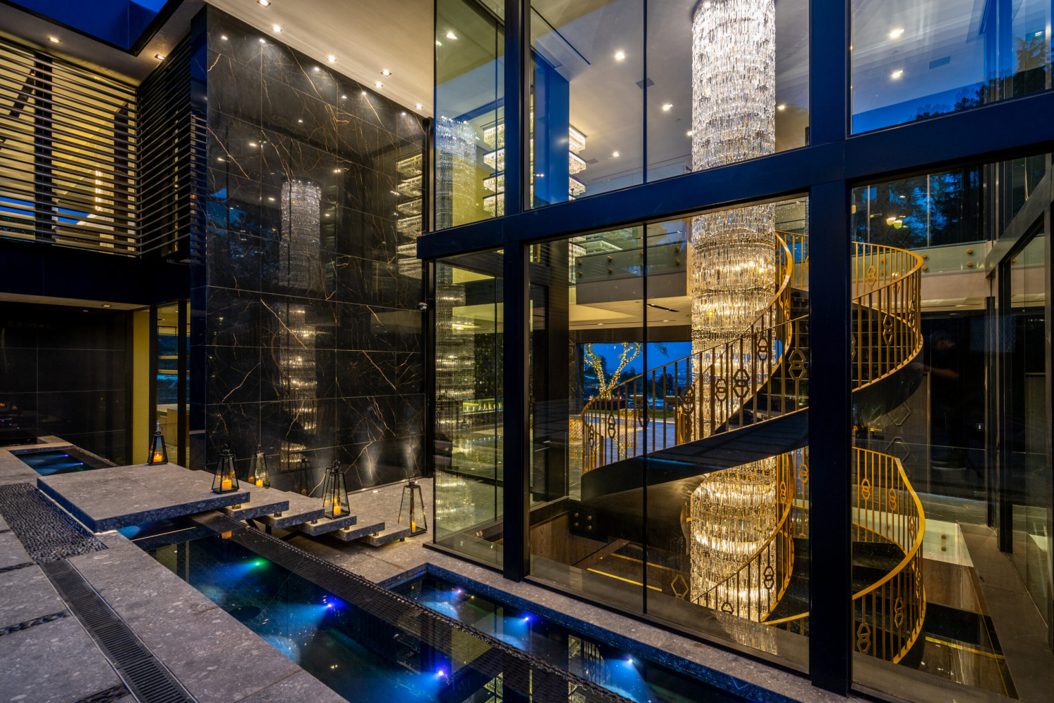 Grand entry showcasing a sculptural staircase, dramatic crystal chandeliers, and contemporary luxury architecture.