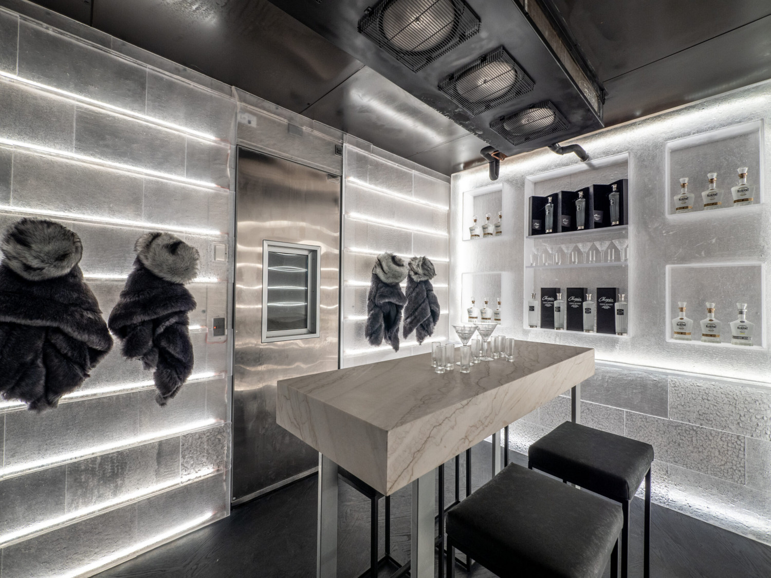 Luxury ice room with illuminated walls, custom tasting table, premium spirits display, and unique entertaining space.