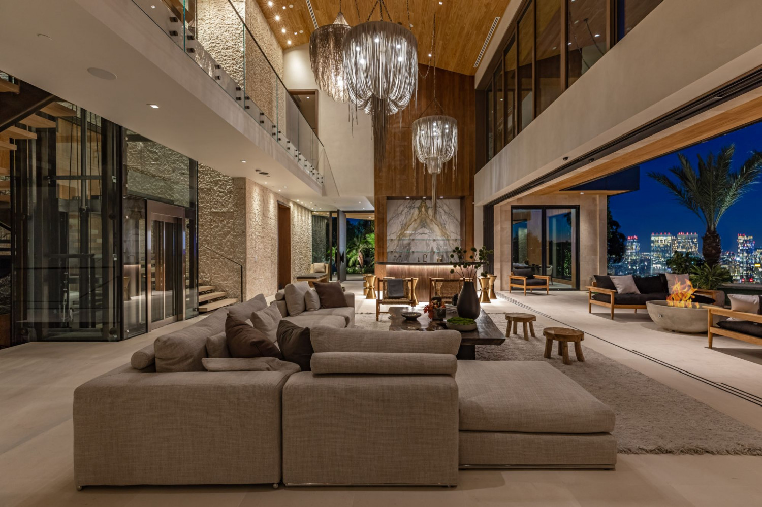 Grand contemporary great room with soaring ceilings, designer chandeliers, floor-to-ceiling glass, and seamless indoor-outdoor living in a Beverly Hills estate.