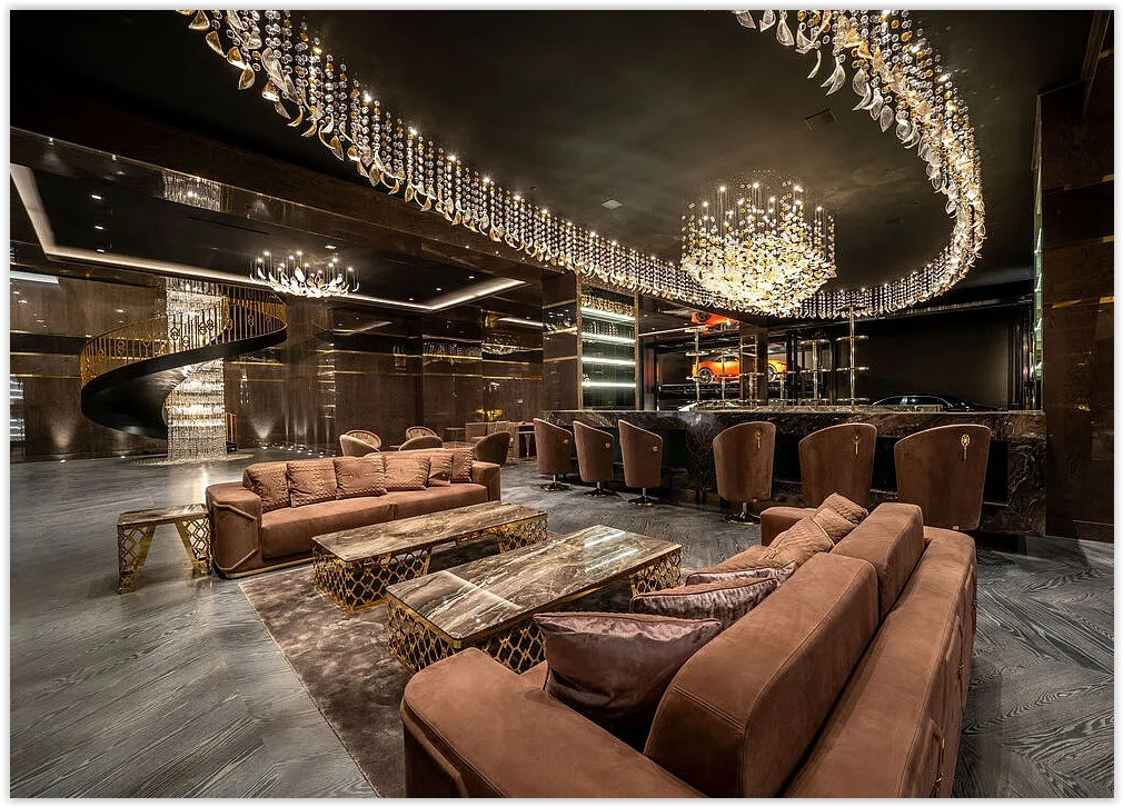 Designer entertainment lounge with custom bar, dramatic chandeliers, luxury finishes, and collector car display.
