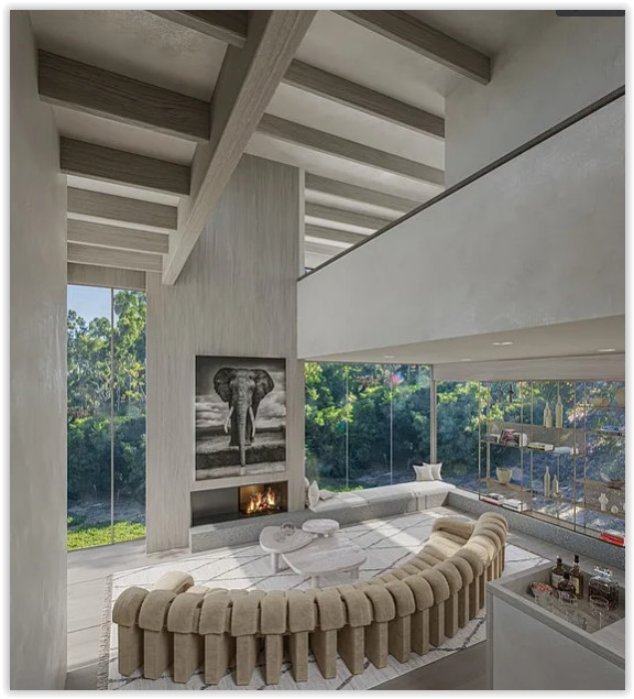 Contemporary great room featuring soaring ceilings, floor-to-ceiling windows, a modern fireplace, and elegant designer furnishings in a Malibu estate.