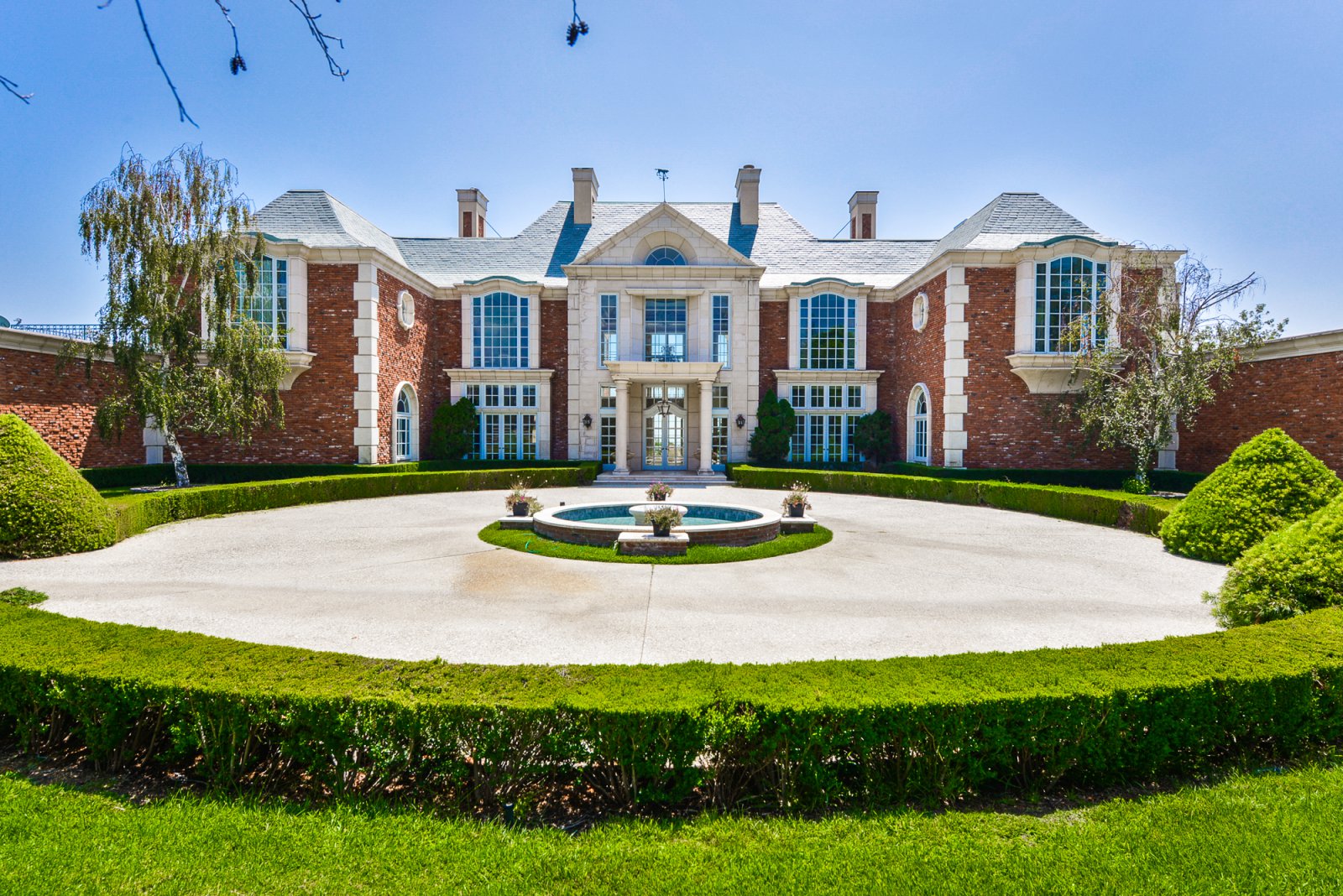 Grand front entrance of a private Pasadena estate featuring a circular fountain, brick architecture, and manicured landscaping.