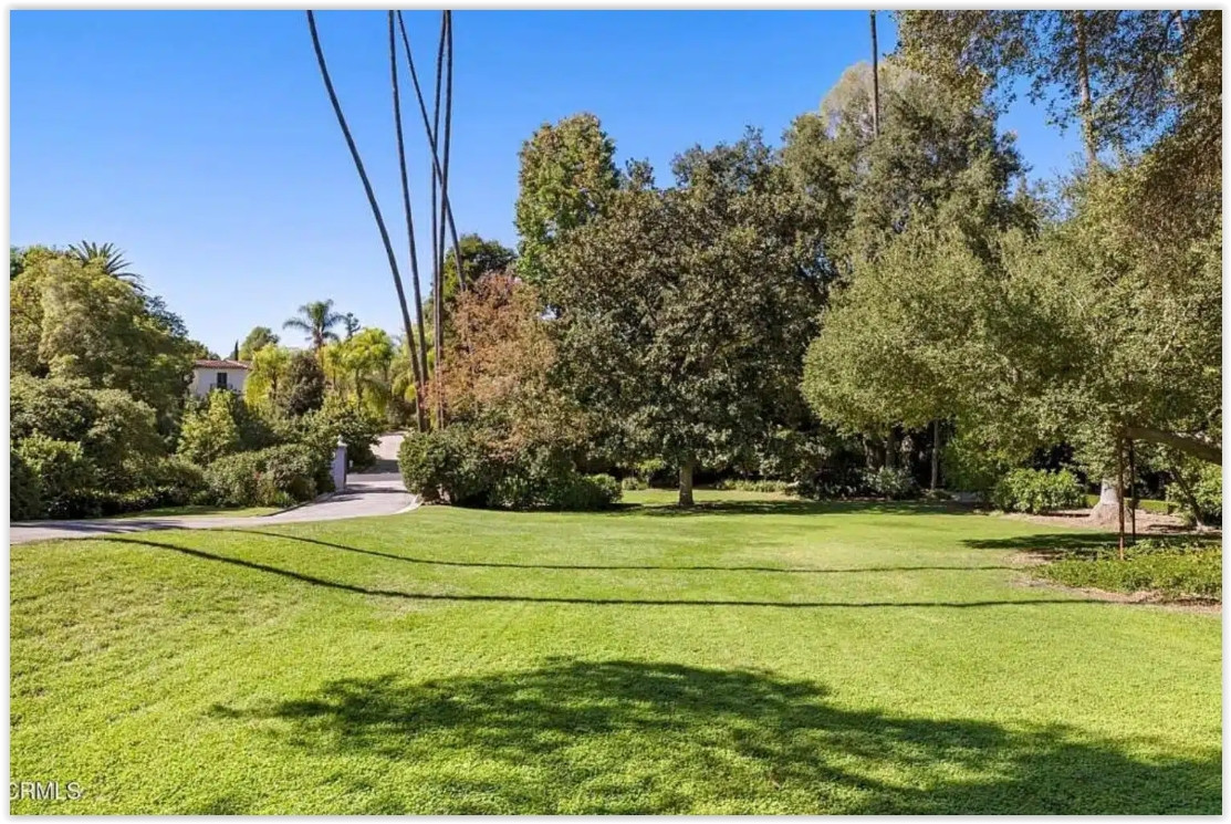Large manicured lawn surrounded by mature trees, ideal for private outdoor gatherings.