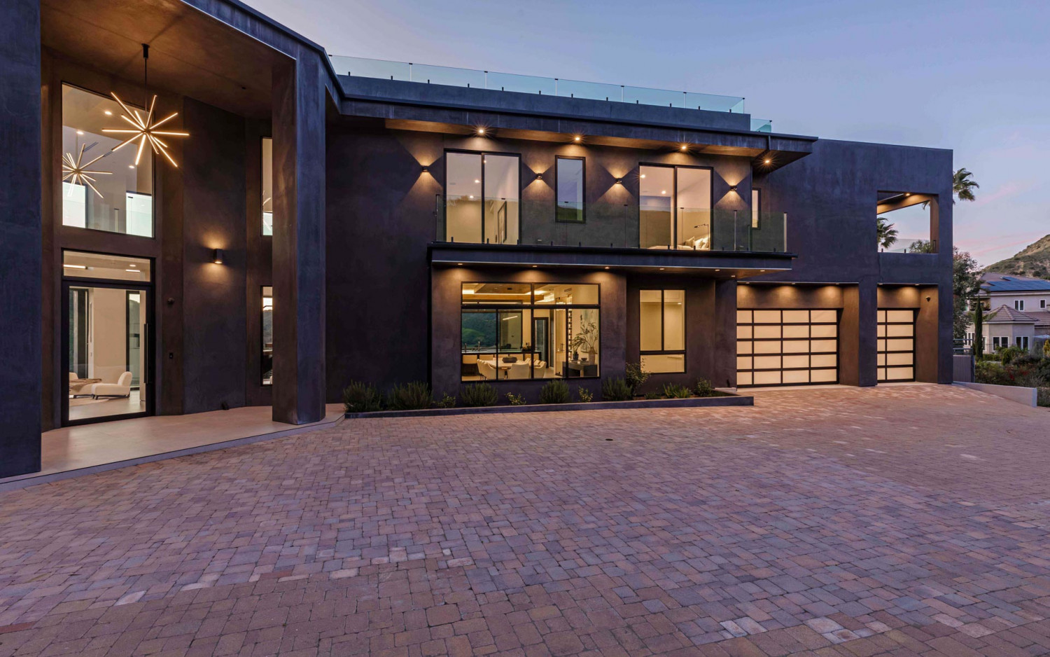 Contemporary hillside estate in Agoura Hills with dramatic modern architecture and illuminated exterior at dusk.