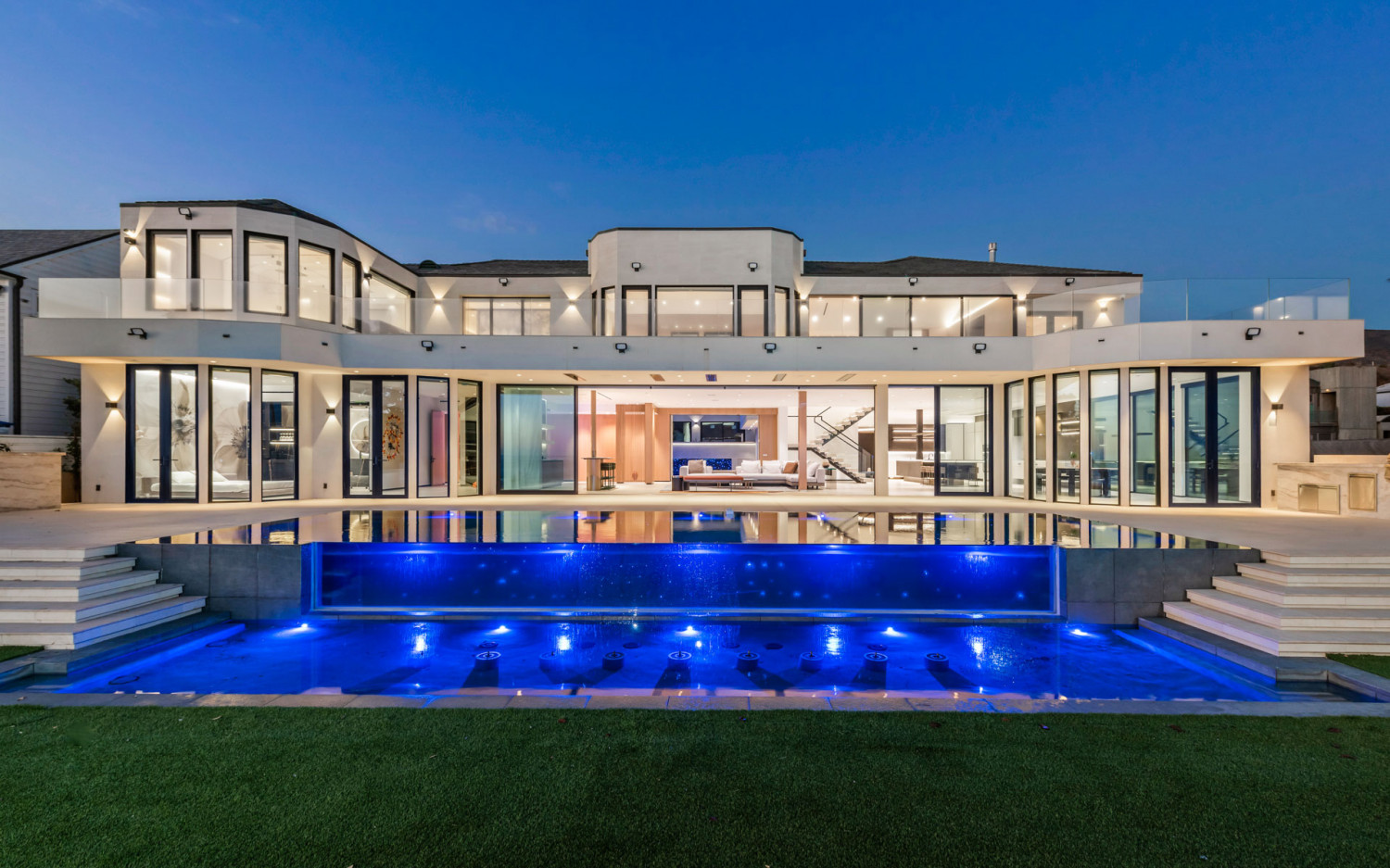 Malibu beachfront estate at night with illuminated pool and ocean backdrop