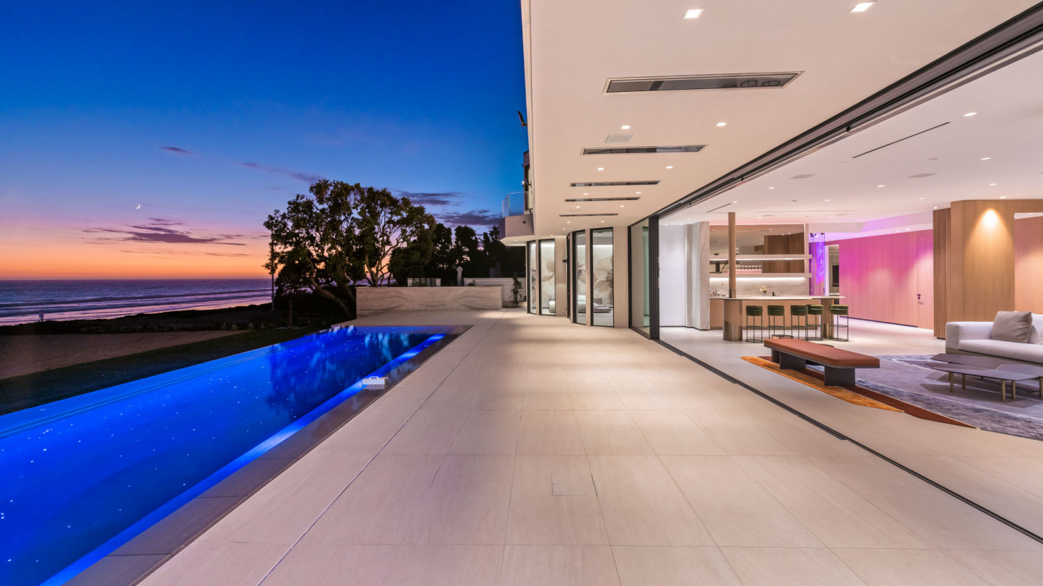 Malibu beachfront estate at night with illuminated pool and ocean backdrop