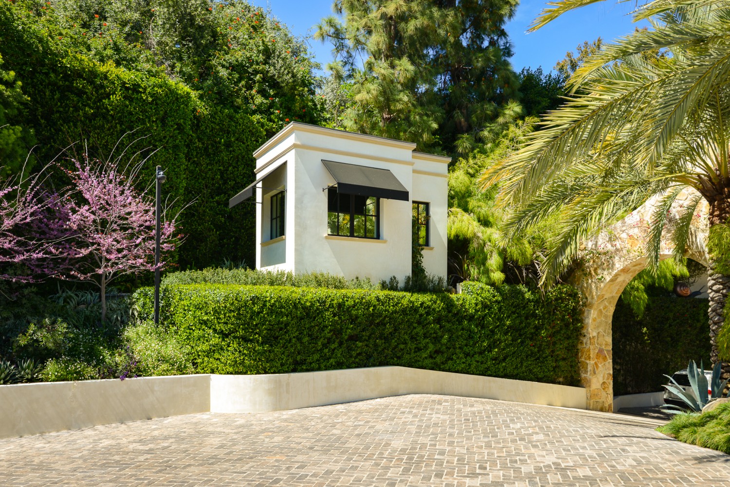 Private Bel Air estate arrival area with landscaped motor court, mature trees and stone archway