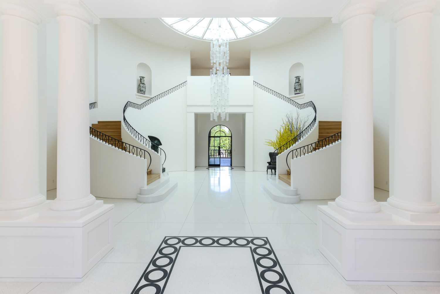 Elegant entry hall with classical columns, patterned flooring and custom front door