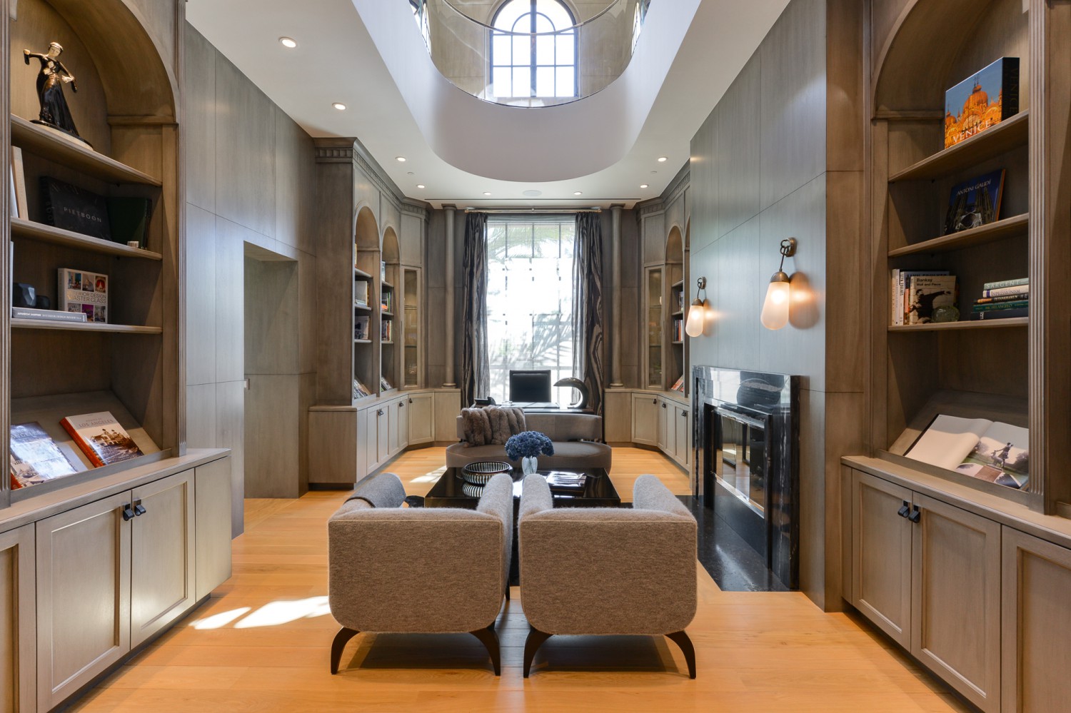 Elegant library with built-in shelving, fireplace and skylit sitting area