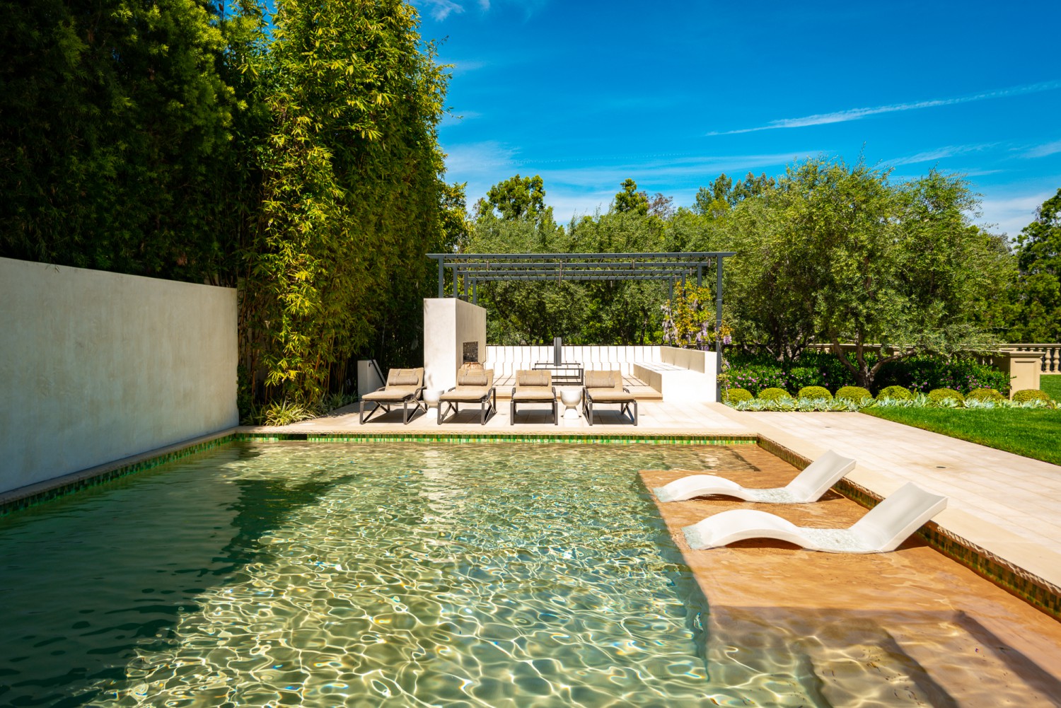 Outdoor swimming pool with lounge seating, mature landscaping and private garden setting
