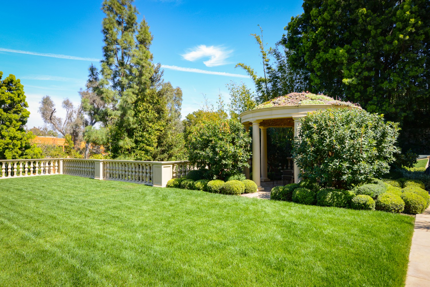 Landscaped garden with manicured lawn, classical pavilion and mature trees at Bel Air estate