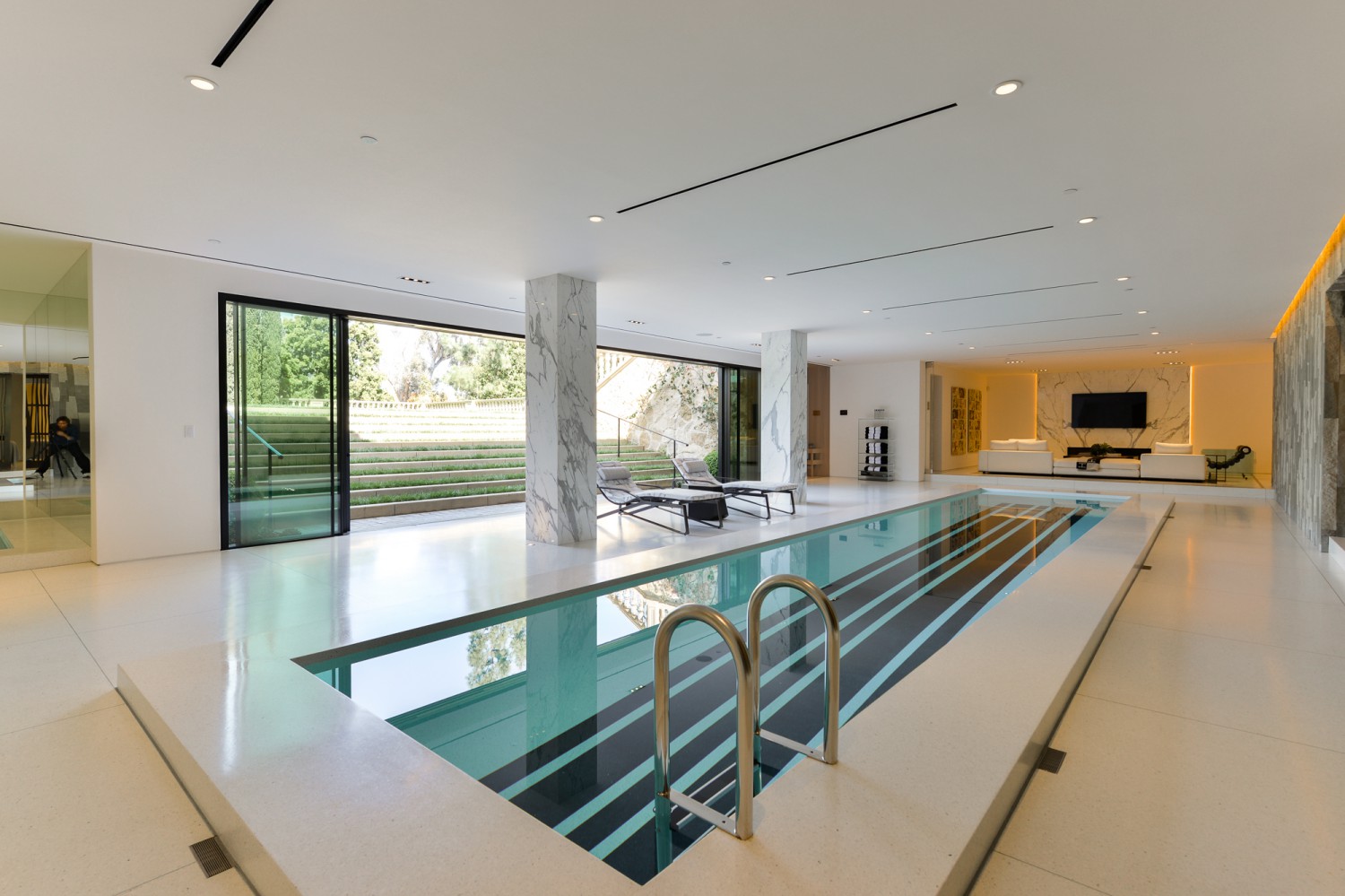 Indoor lap pool with marble columns, contemporary stone walls and bright modern finishes