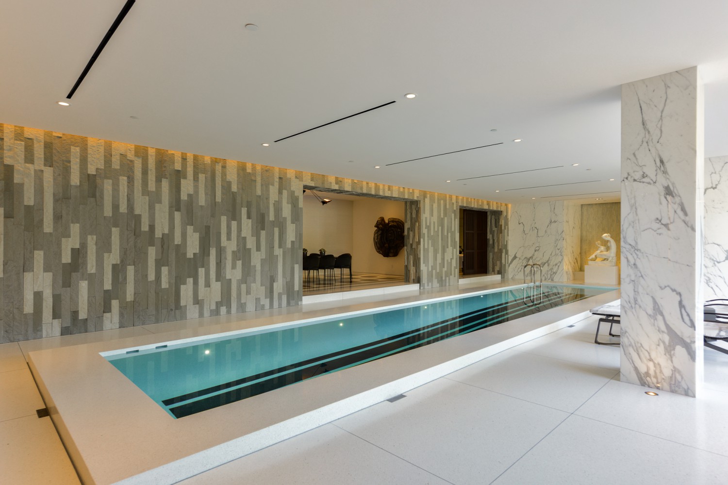 Luxury indoor swimming pool with marble columns, lounge seating and garden views at Bel Air estate