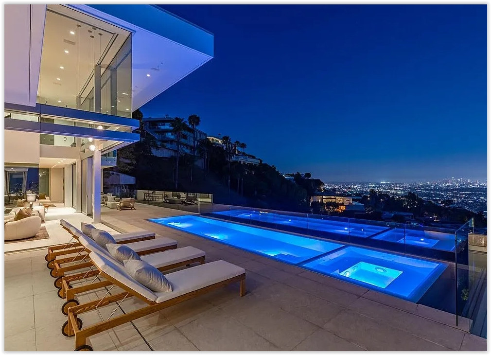 Illuminated infinity pool and poolside terrace overlooking Los Angeles city lights at night