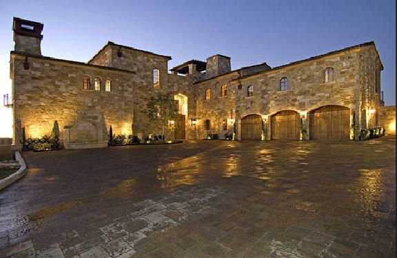 Stone exterior and expansive motor court at a Malibu private estate at dusk