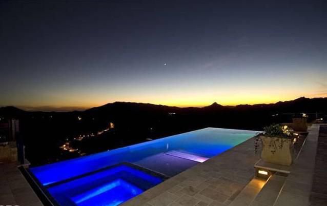 Illuminated infinity pool with sweeping mountain views at sunset in Malibu