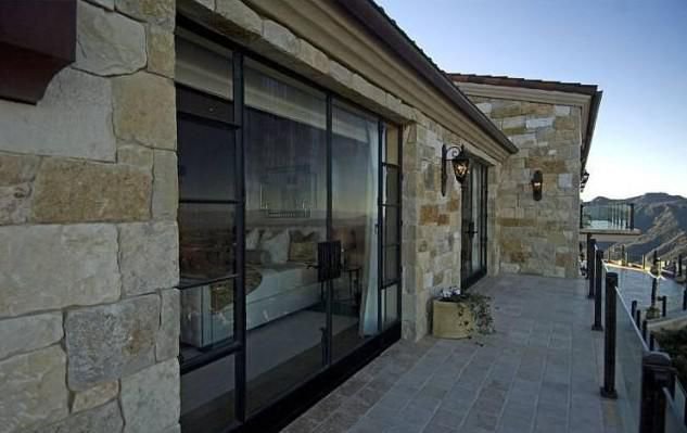 Stone balcony and floor-to-ceiling windows overlooking the Malibu hills