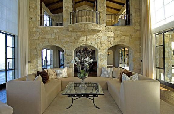 Double-height great room with natural stone walls, tall windows, and warm interiors