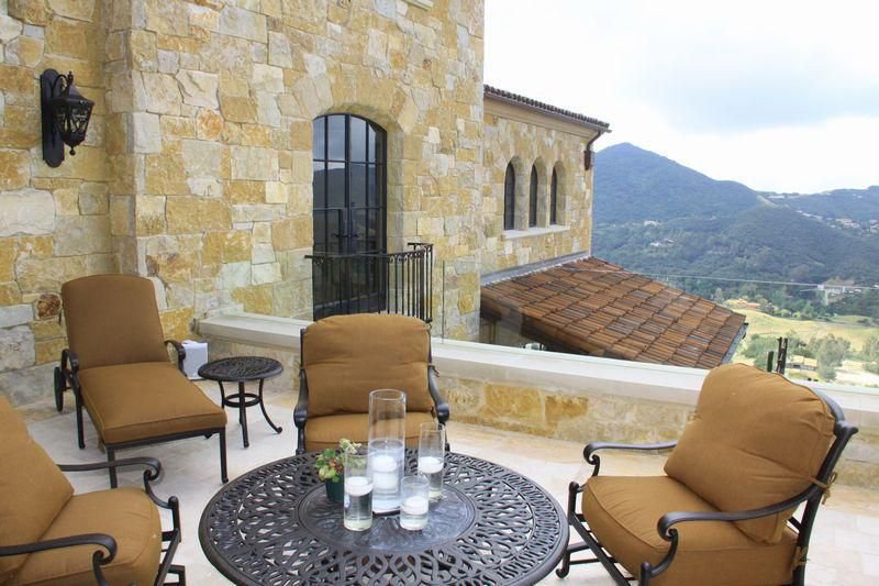 Outdoor terrace seating at a Malibu private estate with stone architecture and mountain views