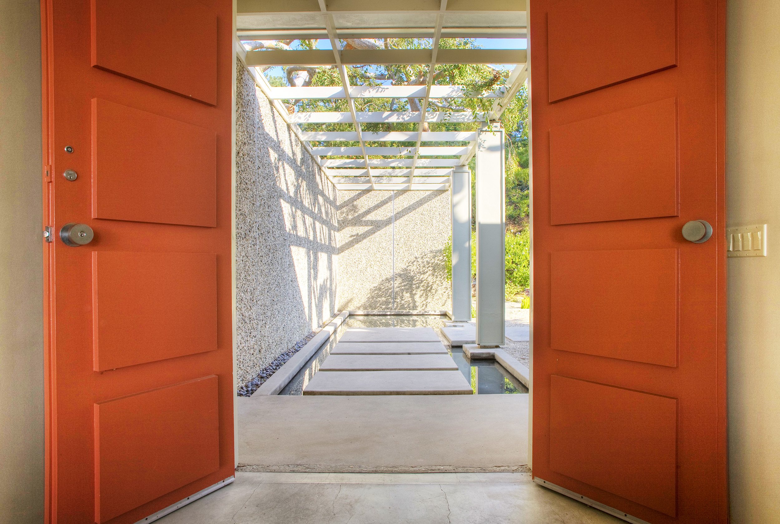 Orange entry doors opening to a covered walkway at a Beverly Hills private event home