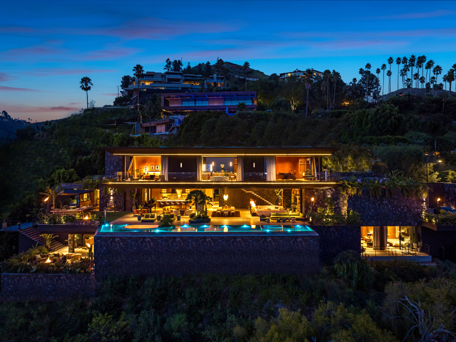 Aerial evening view of modern Los Angeles hillside estate and illuminated pool