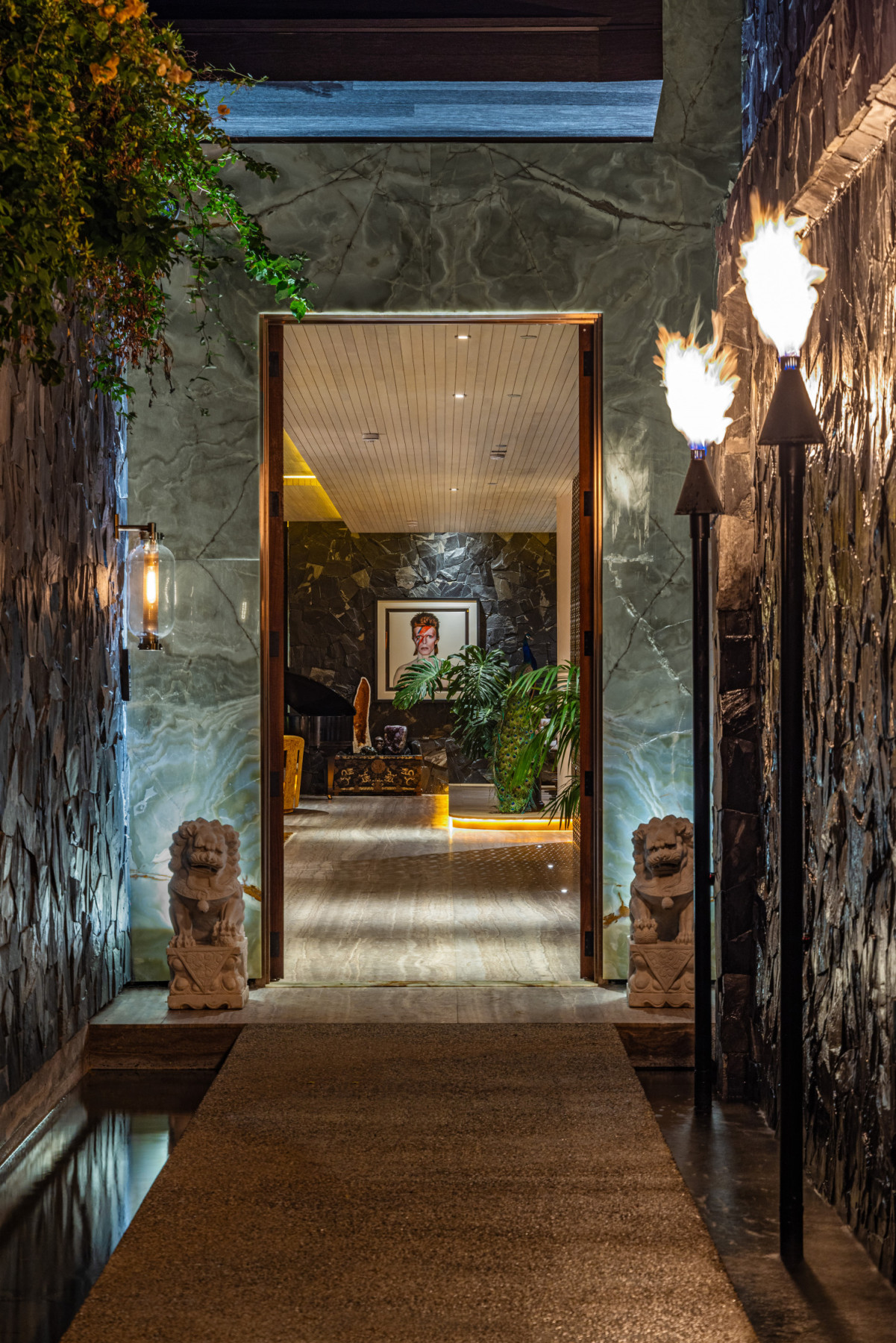 Dramatic stone entry corridor with fire features and illuminated onyx walls