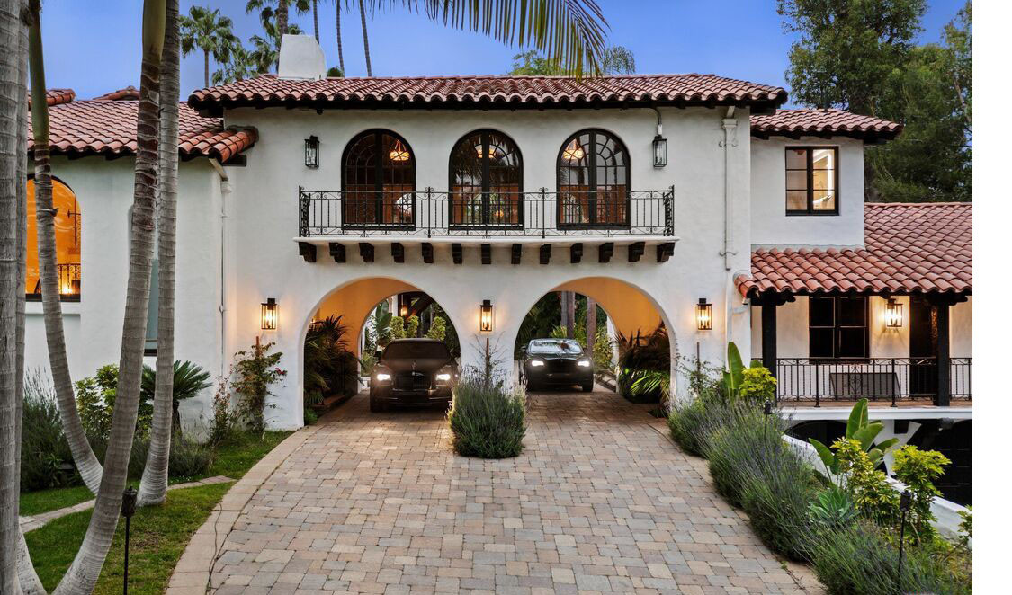 Front exterior of Beverly Hills estate with arched drive-through entry and motor court