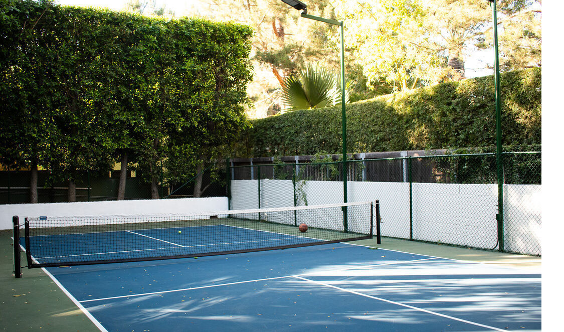 Private tennis court surrounded by mature hedges at Beverly Hills estate